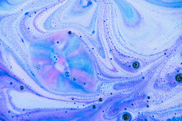 Beautiful bath bomb dissolves in blue, purple and pink colors in the water. Flat lay, top view,...