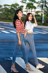 Two girls in jeans are taking pictures in the street