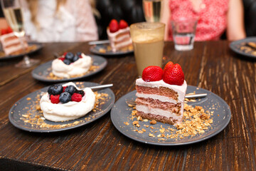 Sweet cakes with summer berries on a wooden table. Party, sweet table. Summer offer desserts in the restaurant.