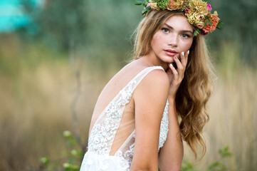 Bride. Beautiful woman in flower wreath and beautiful dress outdoor. 