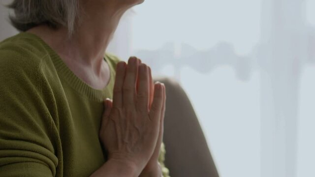 Thankful old woman clasping hands to pray happy smile on wrinkled face, religion