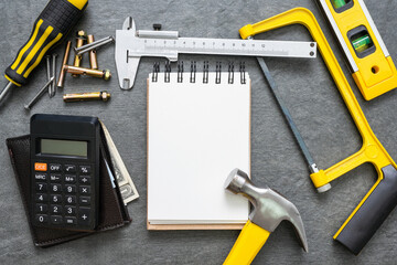 Construction cost or repair calculation mockup. Blank page notepad and work tools on the workbench.
