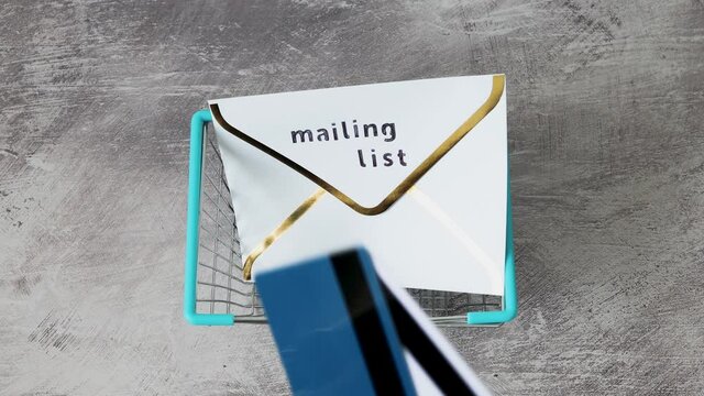 email marketing and online sales, hand placing Mailing List email envelope icon and payment cards inside shopping cart