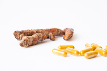 Selective focus shot of turmeric herb, capsule on isolate white background. Alternative, natural healthcare product instead of using medicine.