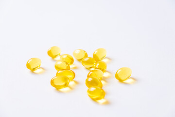 Selective focus of yellow fish oil supplement capsule on isolate white background. Medicine and vitamin for good body nutrition. Healthcare and medical concept.