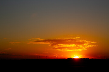 Sunrise with silhouettes of wind turbines on the horizon
