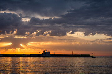 Silhouette of a cargo ship in seaport with the sunrise behind. Sicily in Italy.