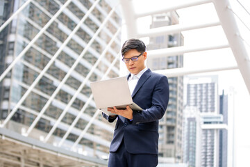 Fototapeta premium young businessman with laptop standing at outdoor.