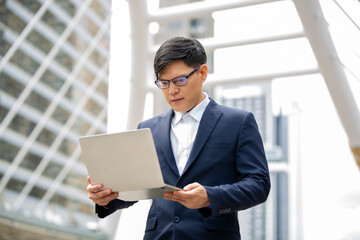 young businessman with laptop standing at outdoor.
