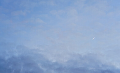 Evening sky with some barely visible clouds, moon crescent in right side - blue hour background