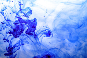 Blue ink injected into water from syringe, colour mixing with water creating abstract shapes