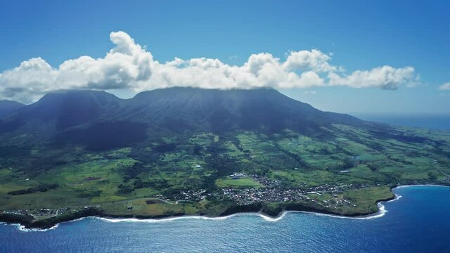 Aerial footage of Mount Liamiuga on a green island with tropical forests and small town in Saint Kitts and Nevis