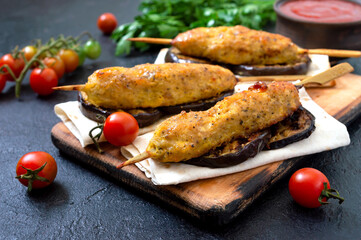 Lula kebab with grilled eggplant on pita bread. chicken kebabs on a skewer with vegetables on the black.