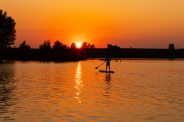 silhouette of a man on paddle board