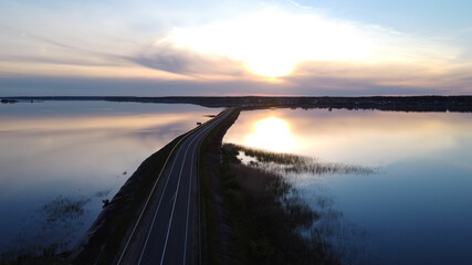 The road among the lake at sunset. Water from all directions. Landscape