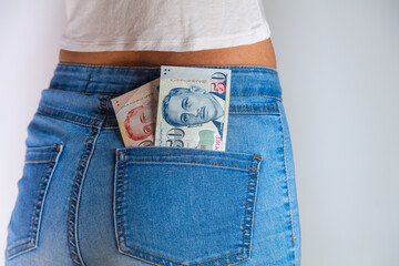 A collection of Singapore dollars in a female jeans pocket. Bunch of Dollar in a female jeans pocket. Singapore banknotes stuck in a woman jeans pocket. Money of Singapore