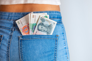 A collection of China Yuan in a female jeans pocket. Bunch of Renminbi in a female jeans pocket. Chinese banknotes stuck in a woman jeans pocket. China Money
