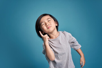 Fototapeta premium Beautiful asian little kid show wonder, imagine, think, or hesitate. Empty space in studio shot isolated on colorful blue background. Education concept for school.