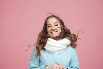 Happy young woman in a winter jacket and scarf, hair in the wind.