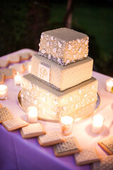 green tiered wedding cake at night on table with candles and cookies