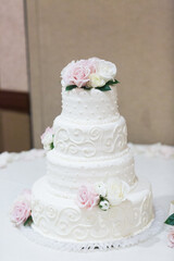 traditional white tiered wedding cake with roses on top