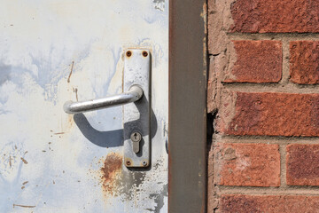 Close Up of Handle & Lock on Old Door  with Brick Wall in Sunlight 