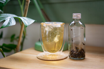 Chinese tea put ice in a clear glass  and empty glass bottle with tea leaves inside put on table in cafe.
