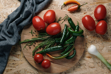 Fresh vegetables mediterranean ingredients with tomatoes, peppers and onions on wooden table with gray cotton kitchen towel