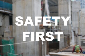 The word SAFETY FIRST is written clearly and against the background of the image of a worker installing a scaffolding. The image has been blurred.