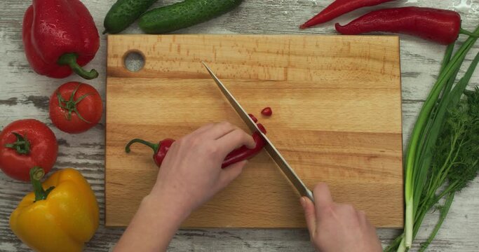 Female hands chop red Ramiro pepper. Top view.