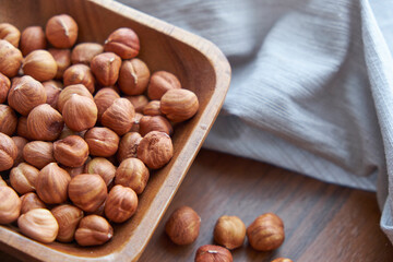 Hazelnut kernels and whole hazelnuts on old brown table, selective focus.