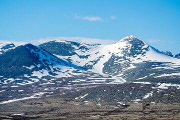 Panoramic shot of beautiful mountain peaks and landscape scenery in spring, with snow capped mountains.