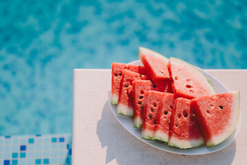 juicy watermelon sliced on plate with swimming pool background. summer vitamins berry.