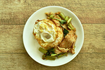spicy fried fermenting pork slice in curry with topping crispy egg on rice egg in plate