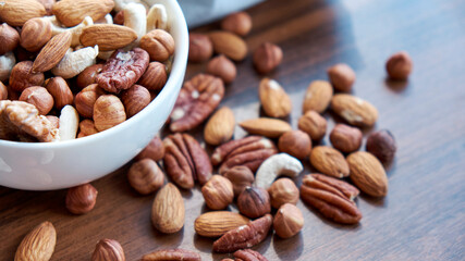 Wooden bowl with mixed nuts on table top view. Healthy food and snack. Walnut, pistachios, almonds, hazelnuts and cashews.
