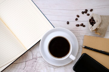 cup of coffee and notebook on wood table background 