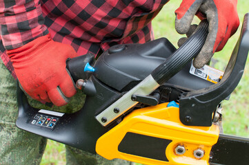 Man in green pants hold orange chainsaw with his bare hands. Close up macro.