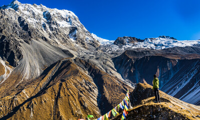 A solo hiker man standing on the ridge at Kyanjin Ri and watching huge snow capped mountains at...