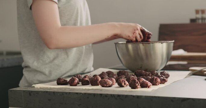 Slow motion handheld shot of young woman making chocolate truffles on home kictchen
