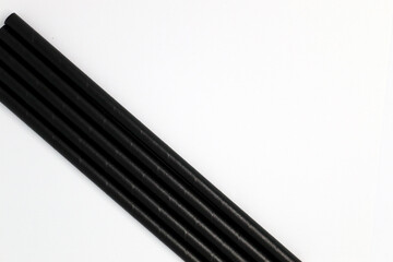 Black drinking paper straws on a white background. 