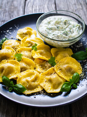 Delicious ravioli with mushrooms and cream sauce on wooden table