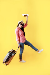 Asian women long hair wear Straw hat with black ribbon in hand holding passport book and travel bag. Female ready to travel with suitcase and passport on yellow background. Summer travel concept.