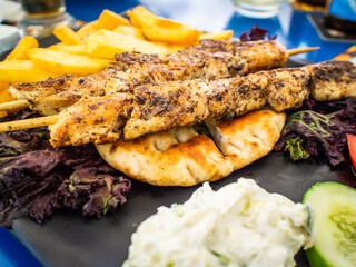 Grilled souvlaki, French fries with tzatziki and fresh vegetables
