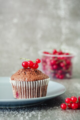 Chocolate muffin with red currants on a gray plate