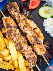 Grilled souvlaki, French fries with tzatziki and fresh vegetables
