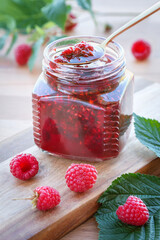 Raspberry jam and fresh berries on a wooden table