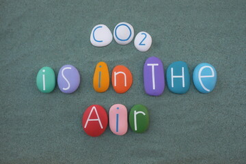 CO2 is in the air, slogan text composed with multicolored stone letters over green sand