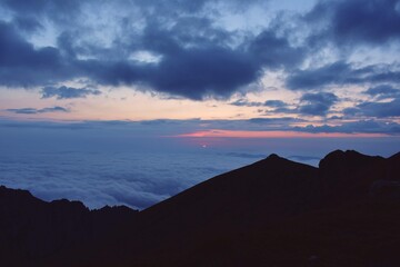 the pink solar disk seen from high altitude at sunrise. alpine sea at the mountain 