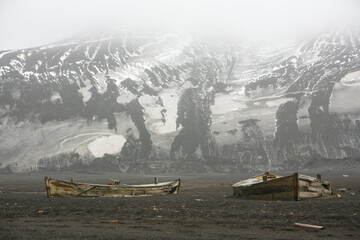 Old wooden boats from an ancient Whaling Station abandoned on the beach of Whalers' Bay in Deception Island, Antarctic Peninsula.