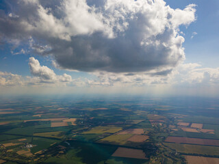 High flight in the clouds over agricultural fields in summer.